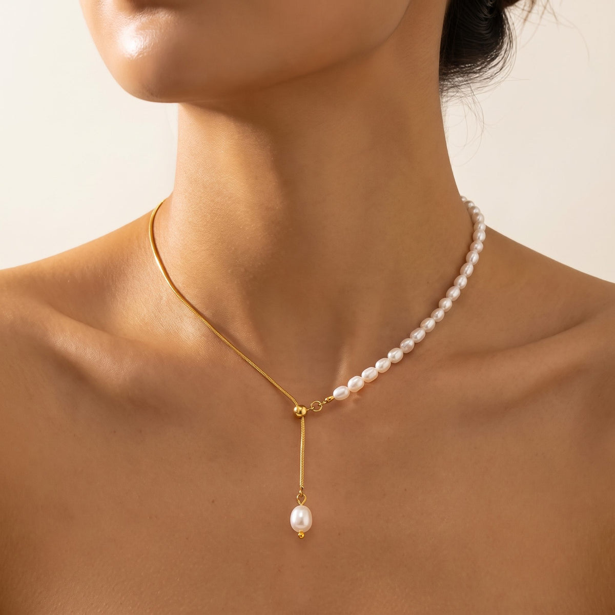 Close-up of a woman wearing the Élise pearl lariat gold necklace at the base of her neck