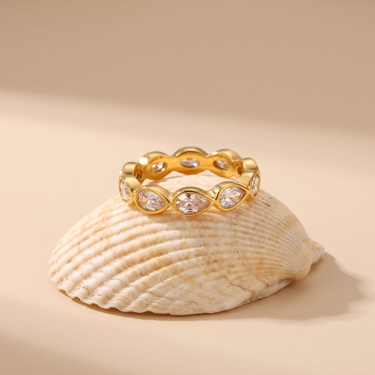 Élodie pear eternity gold ring on a seashell resting on a neutral background
