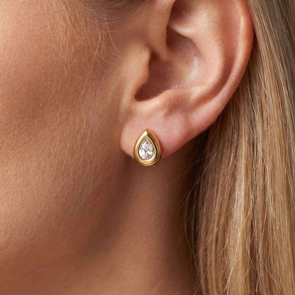 Woman wearing the Élodie teardrop bezel gold earrings on the ear