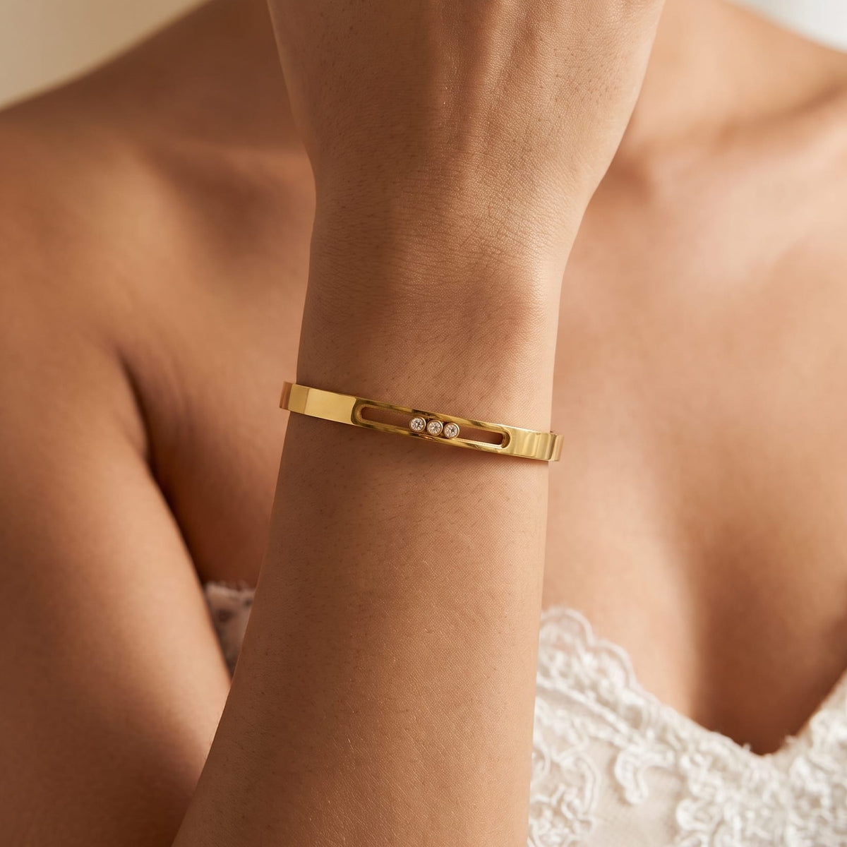 Woman wearing the Elsa sliding crystal gold bangle on her wrist with a lace dress