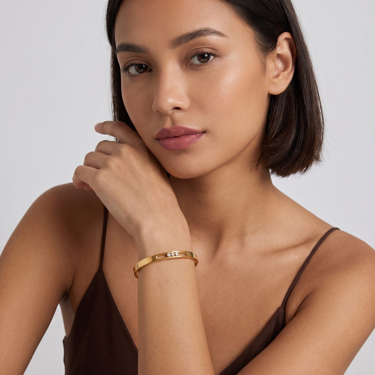 Woman wearing the Elsa sliding crystal gold bangle posing with her hand near her chin