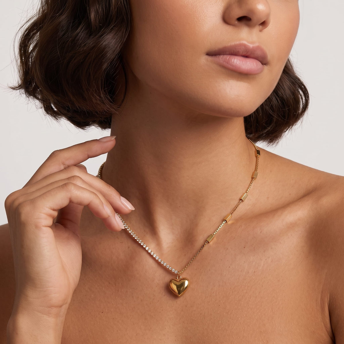 Woman wearing the Ginevra heart tennis gold necklace at the collarbone with short hair
