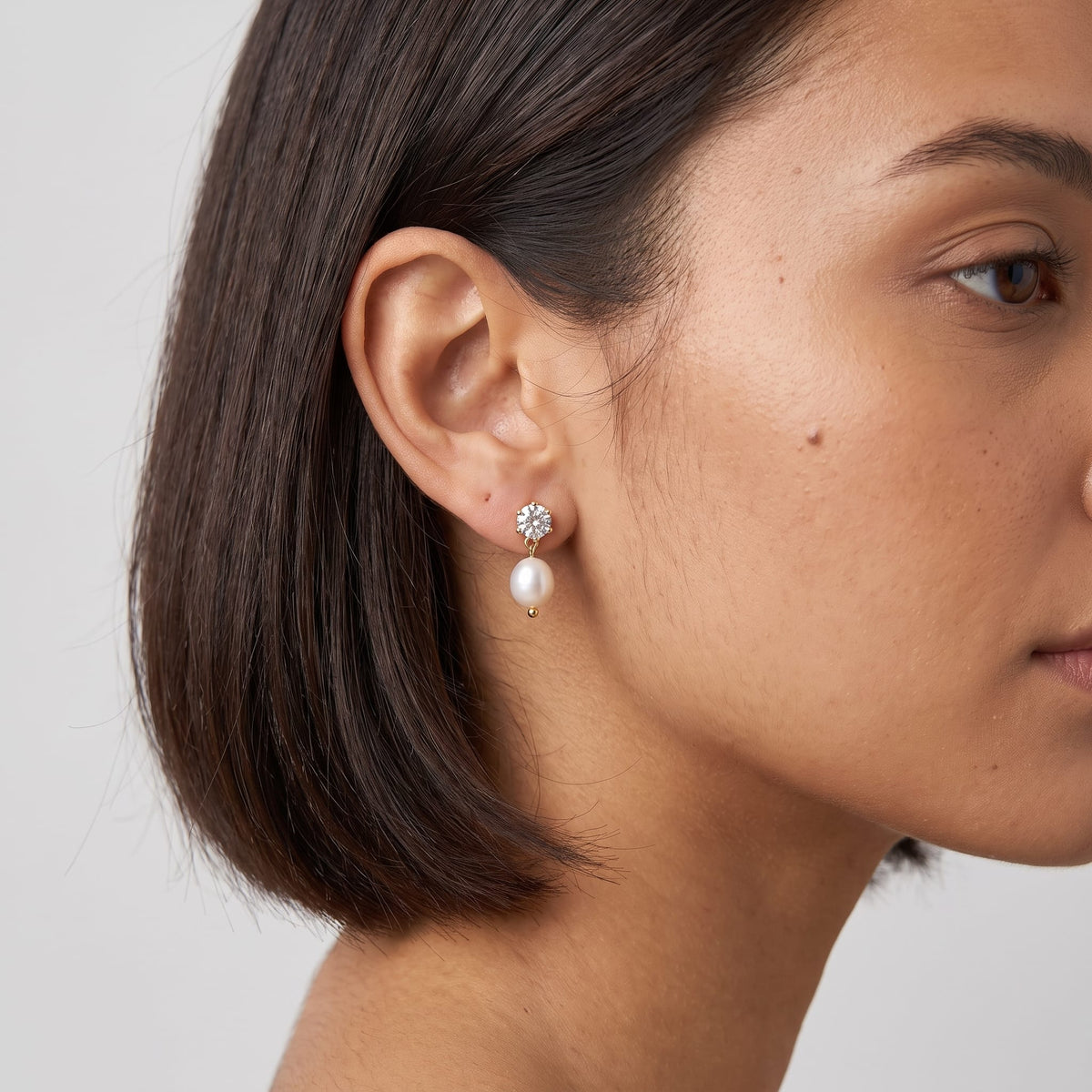 Woman wearing the Ginevra pearl drop gold earrings on the ear in profile with short hair