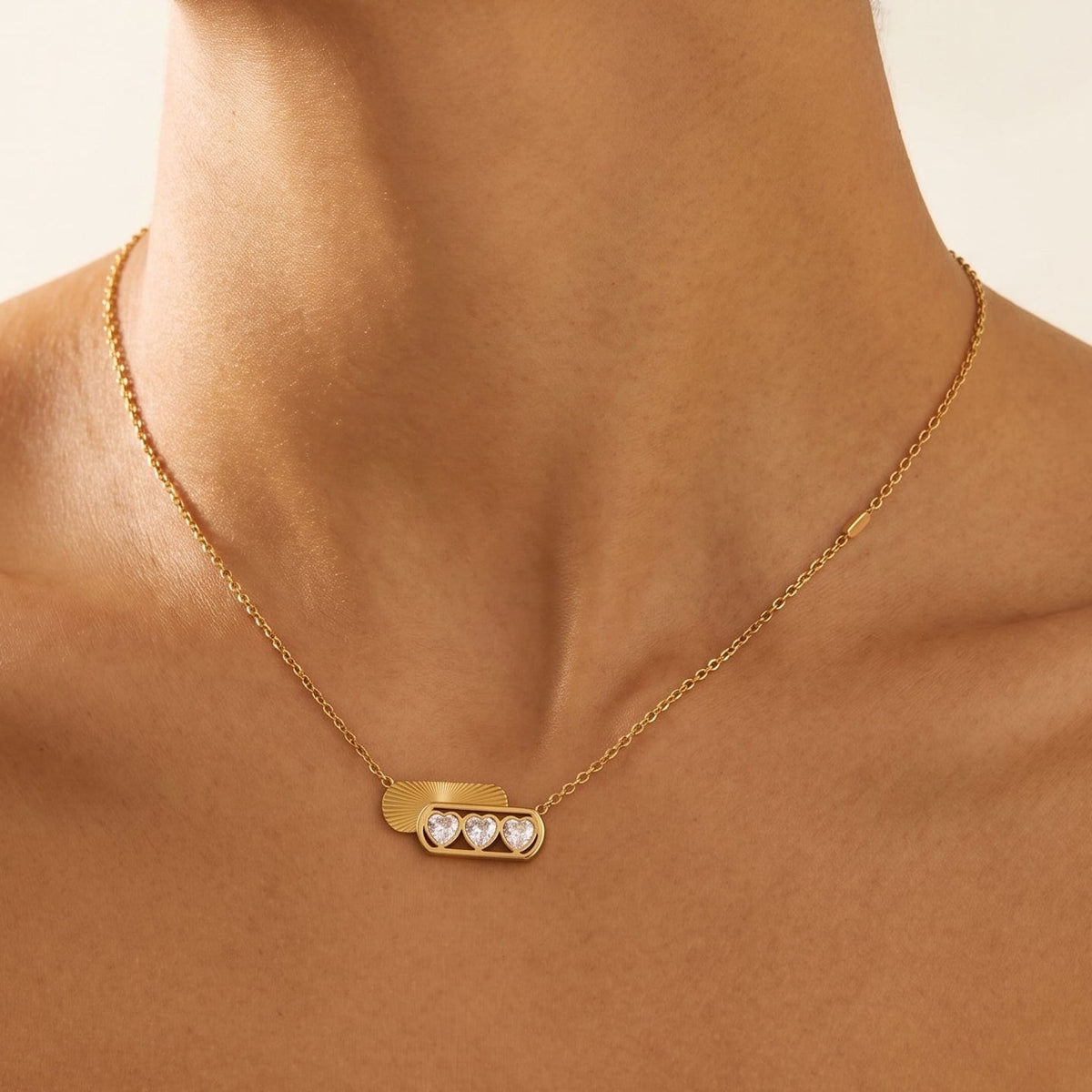 Woman wearing the Ginevra triple heart gold necklace at the collarbone