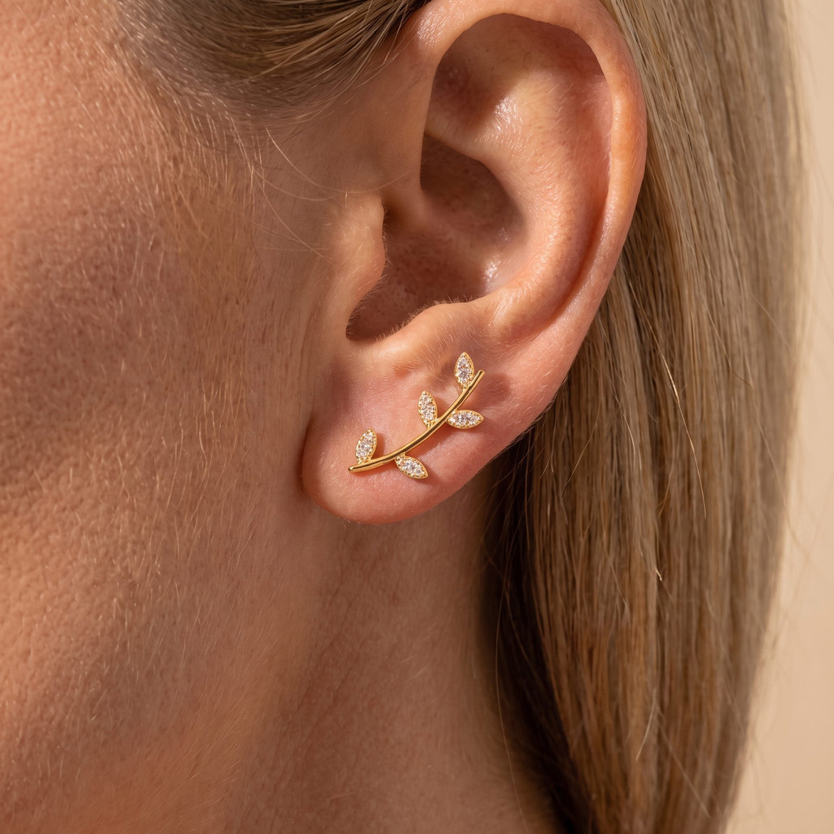 Woman wearing a Giulia gold vine leaf climber with crystal leaves rising from the lobe