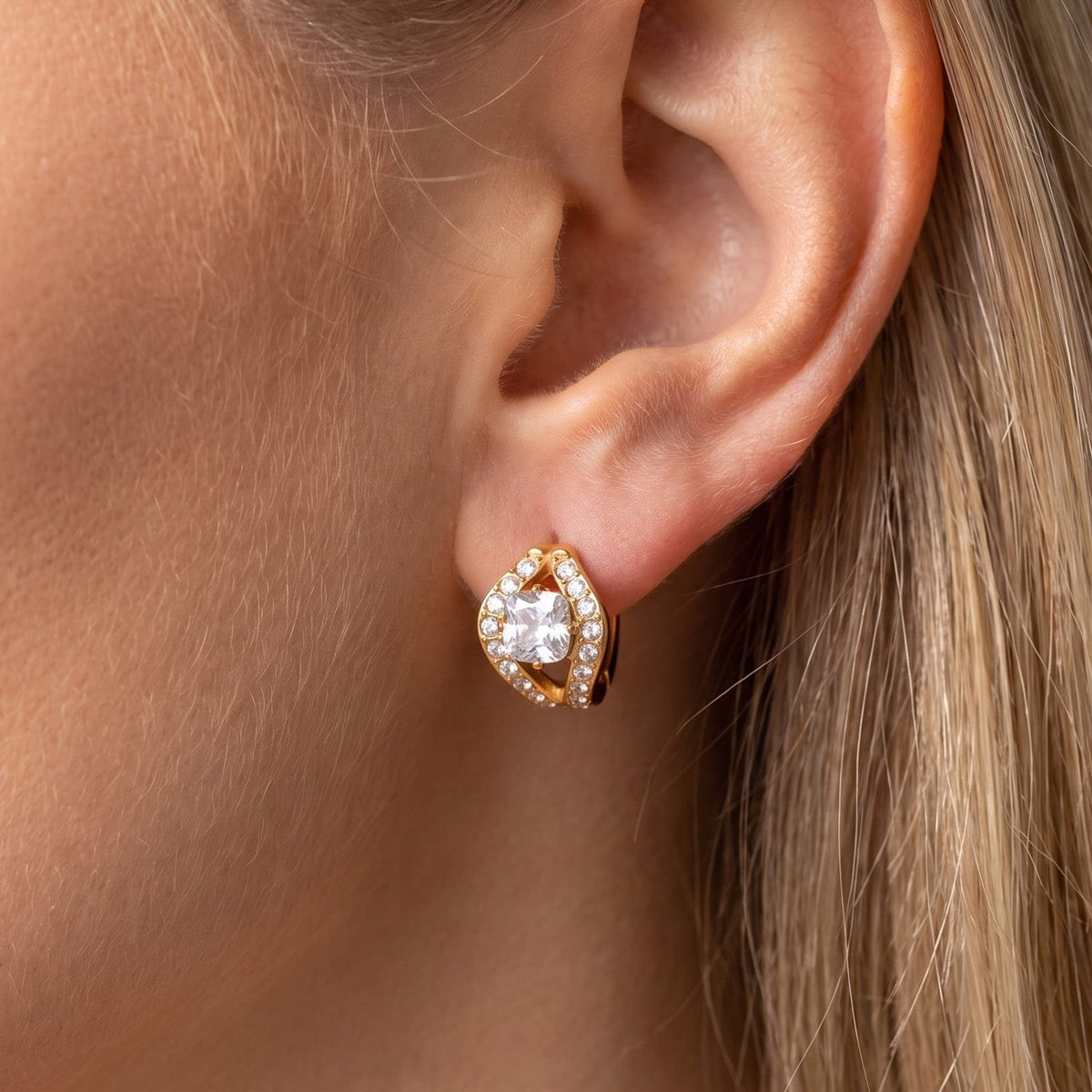 Woman wearing the Ilaria cushion halo gold earrings on the ear, framed by blonde hair