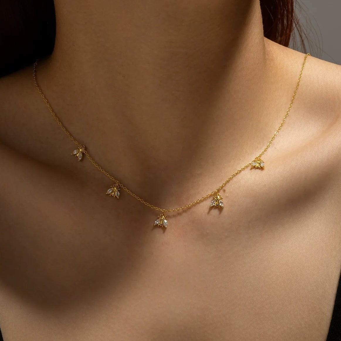Woman wearing the Amélie crystal bee necklace in gold, crystal bee charms spaced along the chain