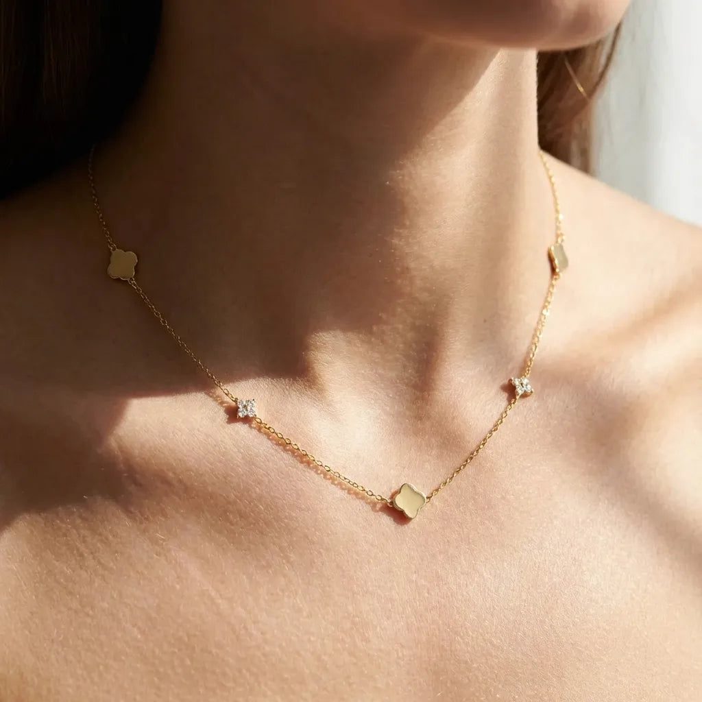 Woman wearing the Inès gold clover necklace with polished clovers and crystal clusters