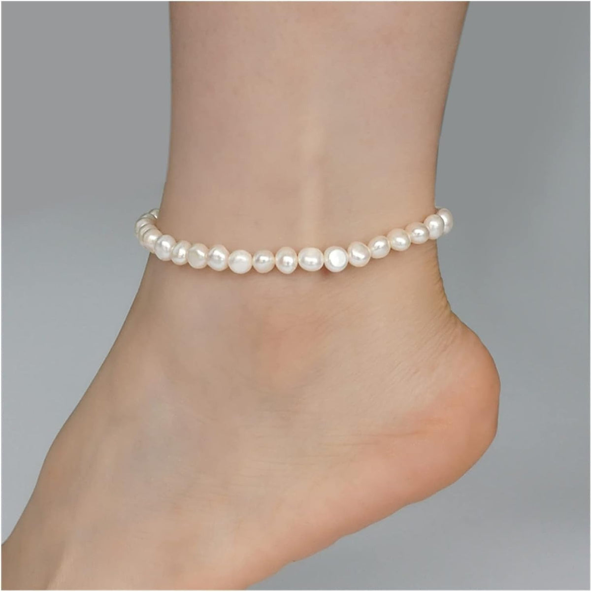 Olivia organic pearl anklet on the ankle, a strand of rounded, slightly irregular white pearls