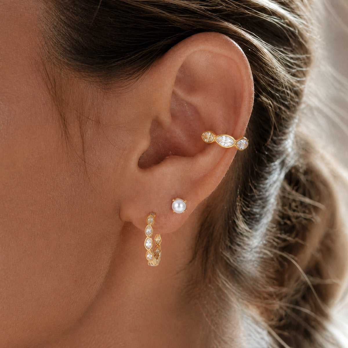 Irène marquise crystal ear cuff worn on the inner rim of the ear above a pearl stud