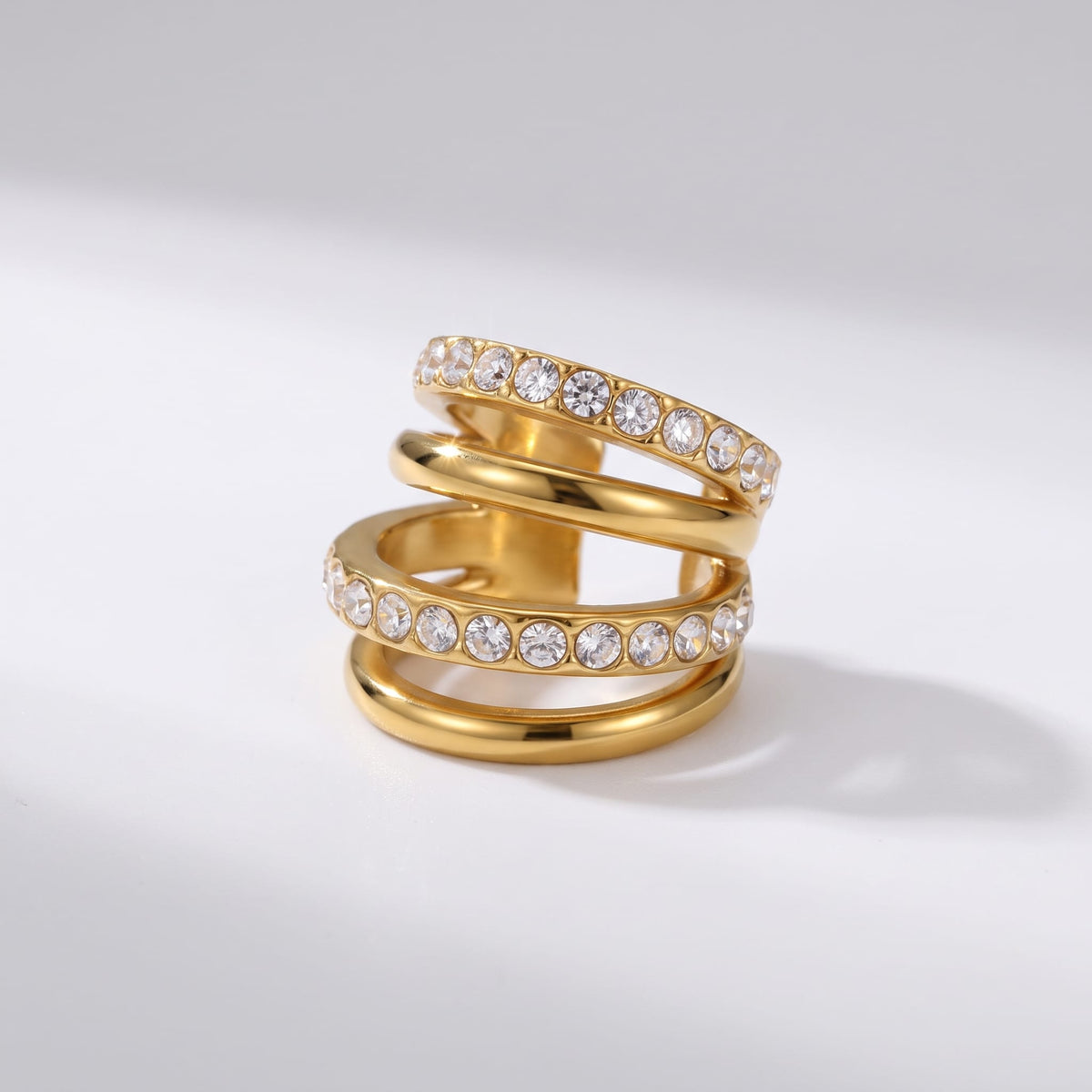 Jeanne crisscross gold ear cuffs on a plain white surface casting soft shadows