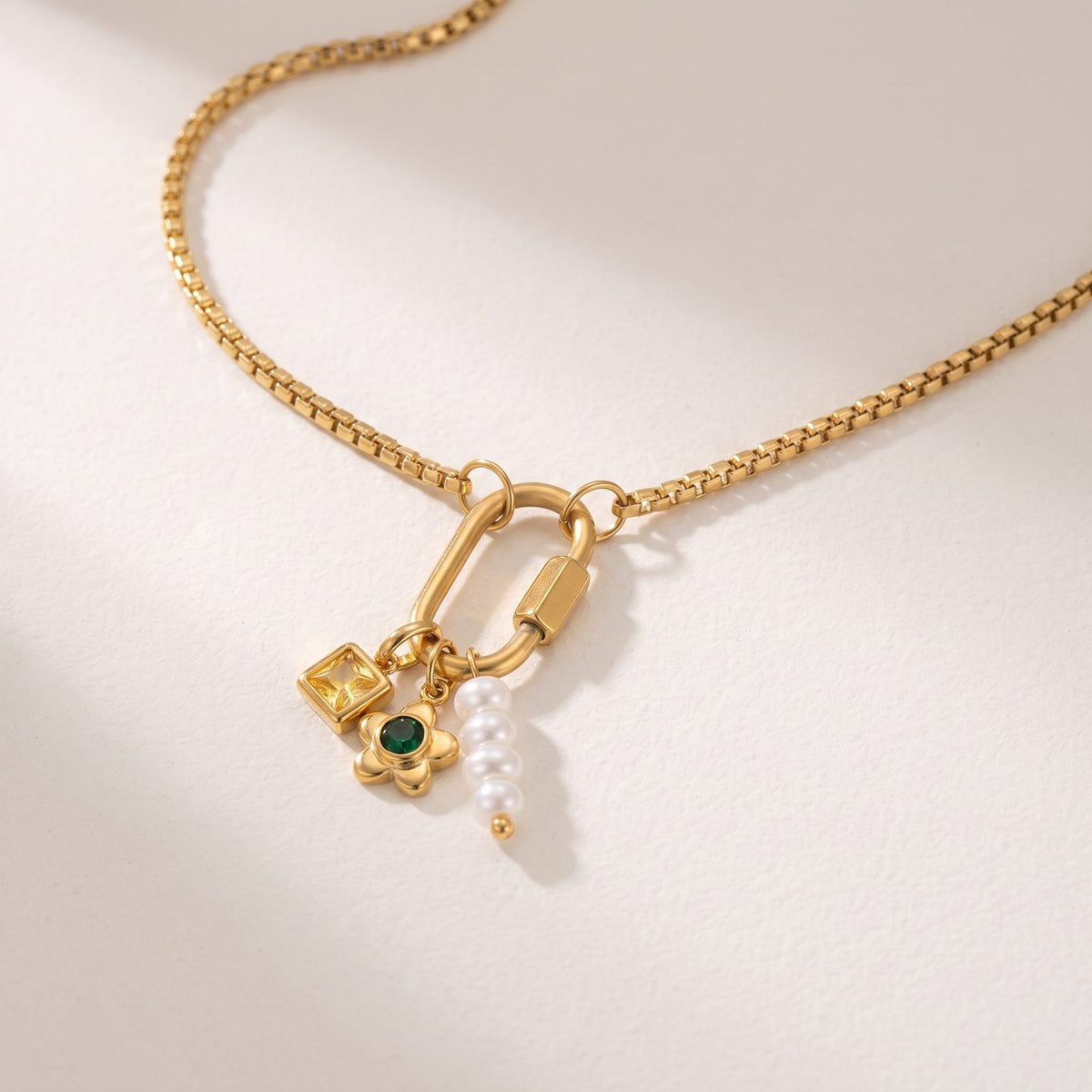 Close-up of the Lilou daisy charm gold necklace on an off-white surface