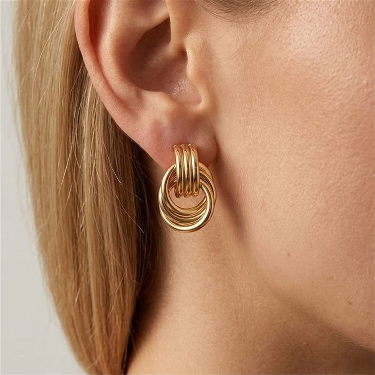 Woman wearing the Luna gold earring with interlocking rings below a ribbed top