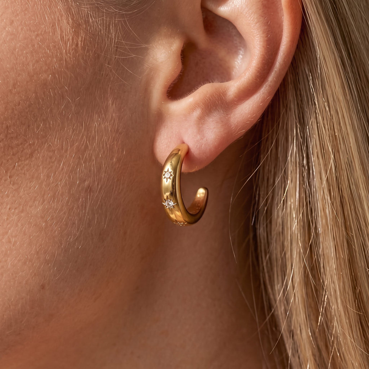 Woman wearing the Luna chunky gold crescent hoop dotted with small star-set crystals