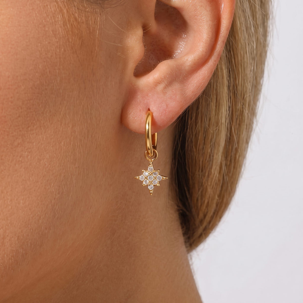 Woman wearing the Margaret gold huggie with a crystal-set star charm