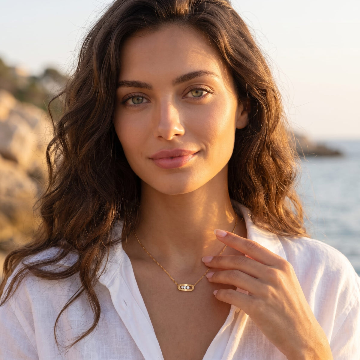 Woman wearing the Margaux sliding crystal gold necklace at the collarbone outdoors in white shirt