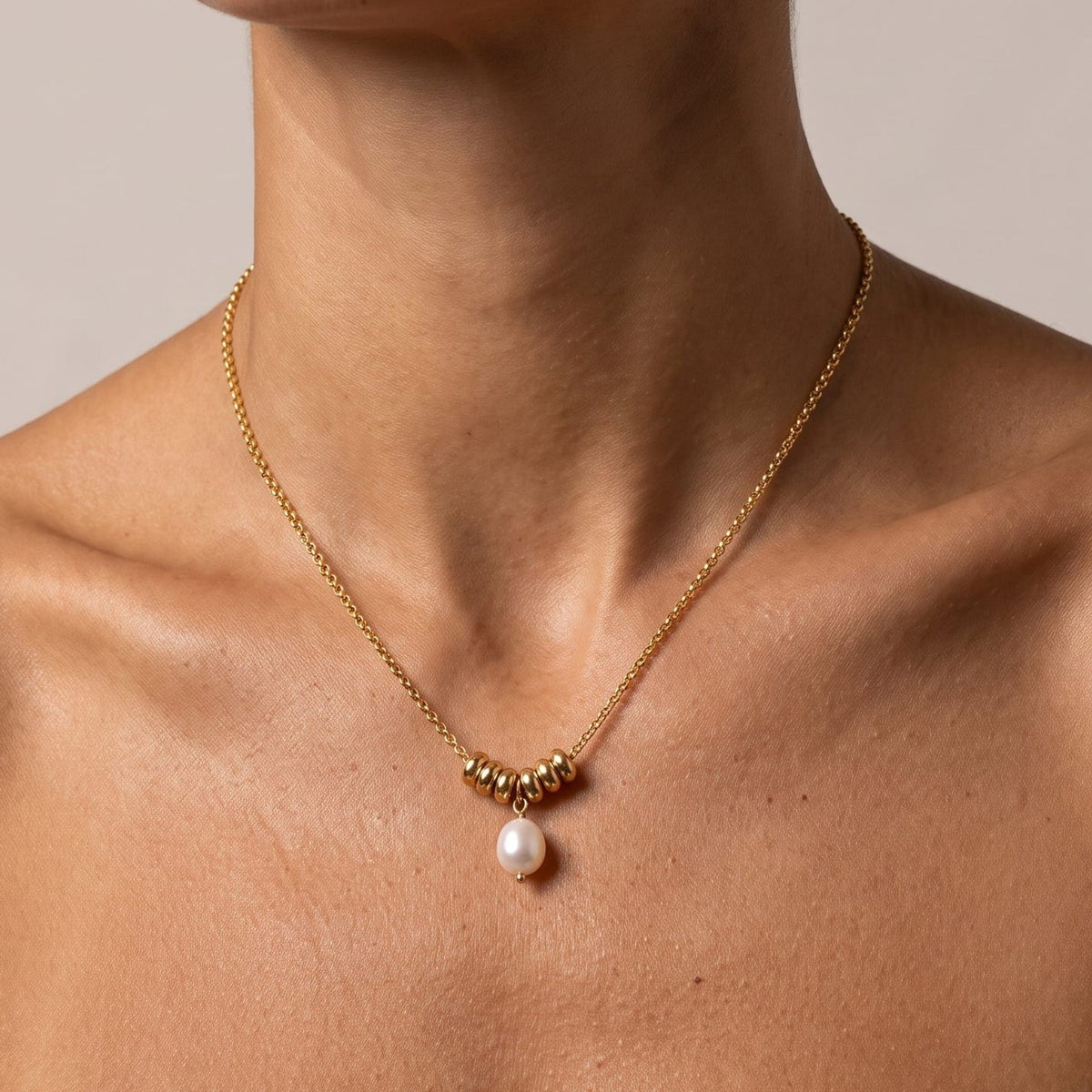 Woman wearing the Mathilde pearl drop gold necklace at the collarbone
