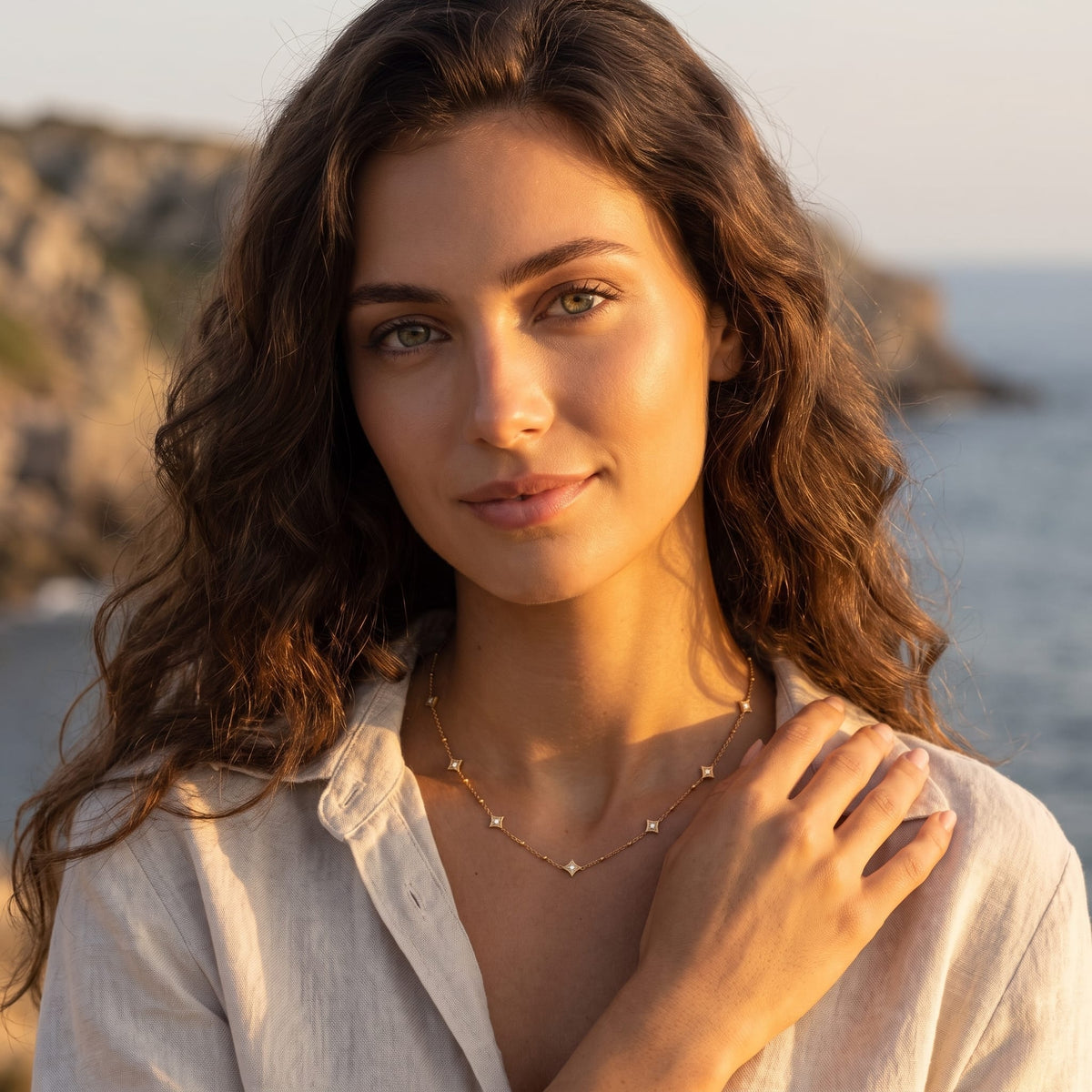 Woman wearing the Océane star station gold necklace at the collarbone outdoors near the ocean
