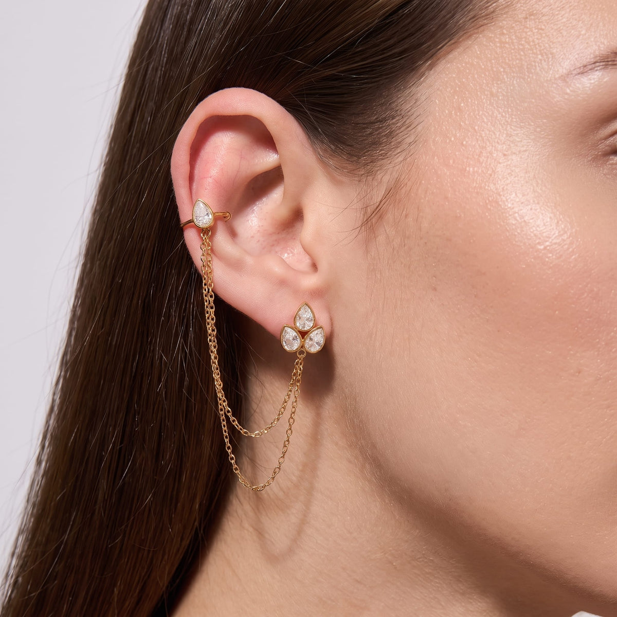 Woman wearing the Ophélie cuff chain gold earrings on her ear, closeup view