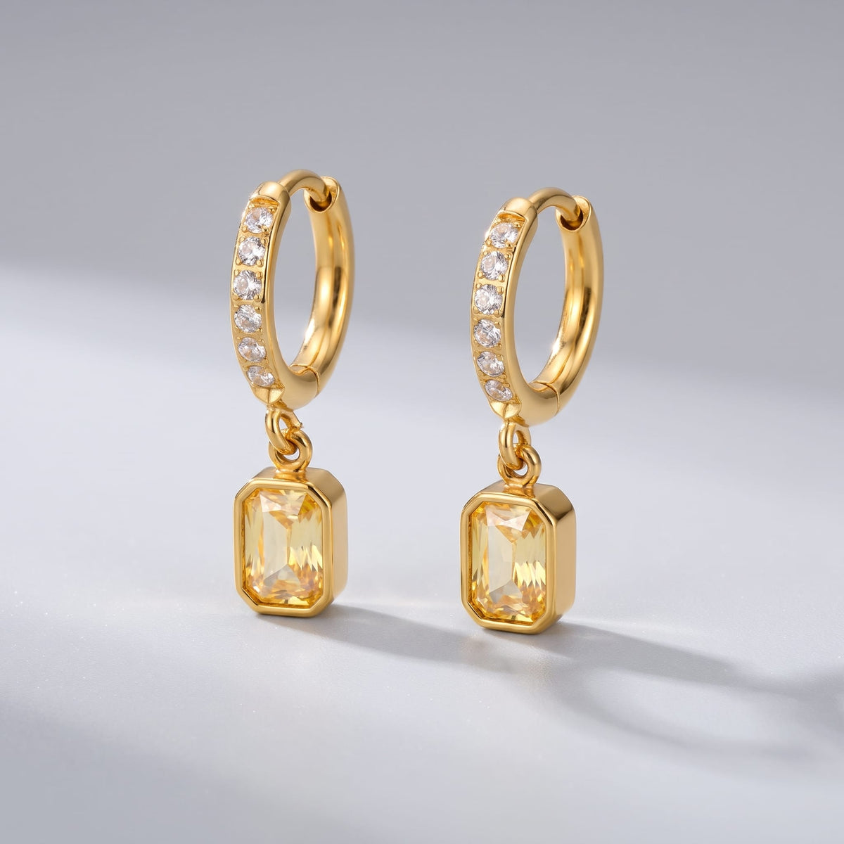 Paola yellow octagon gold earrings on a smooth neutral background