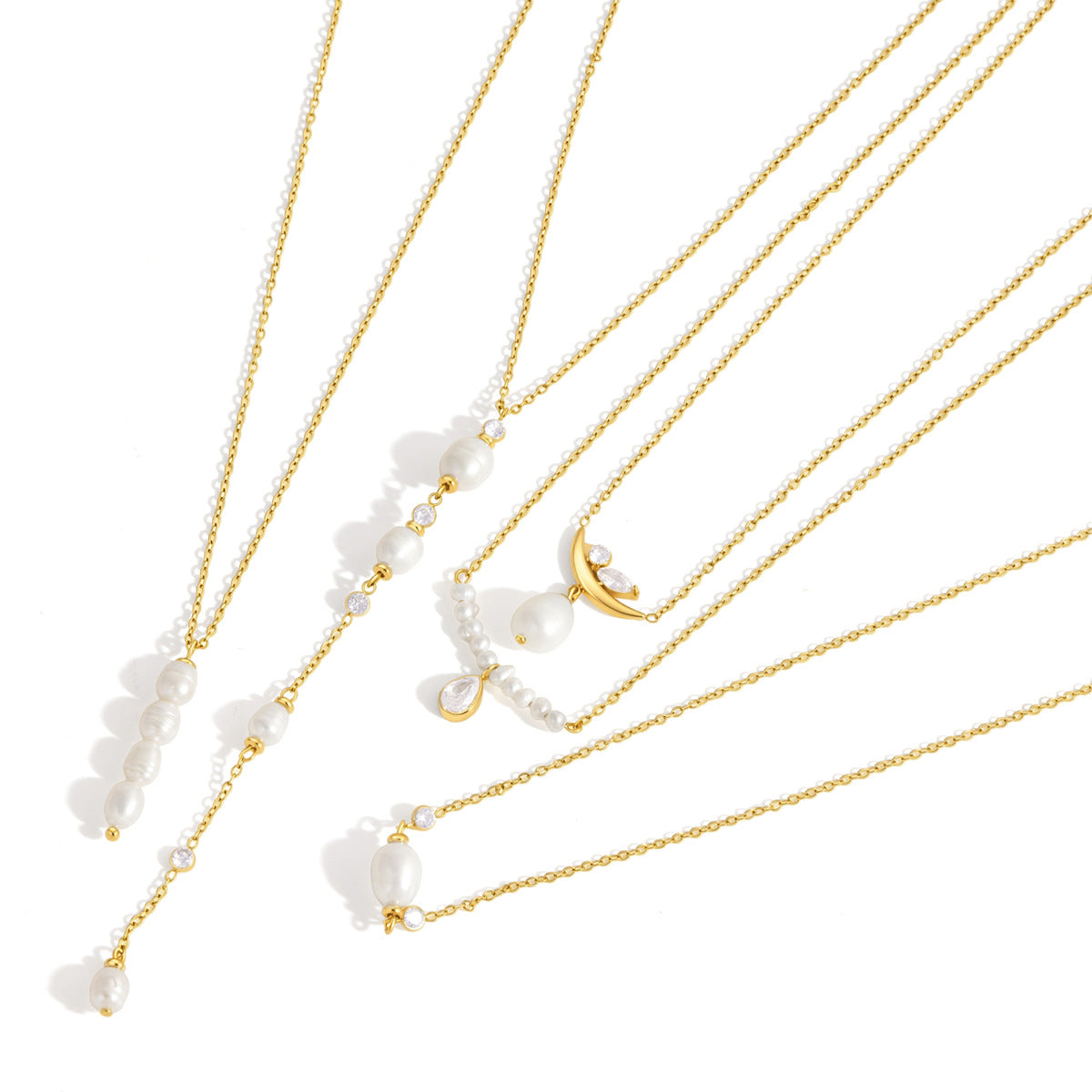 Pauline crescent moon pendant among gold pearl necklaces laid diagonally on white