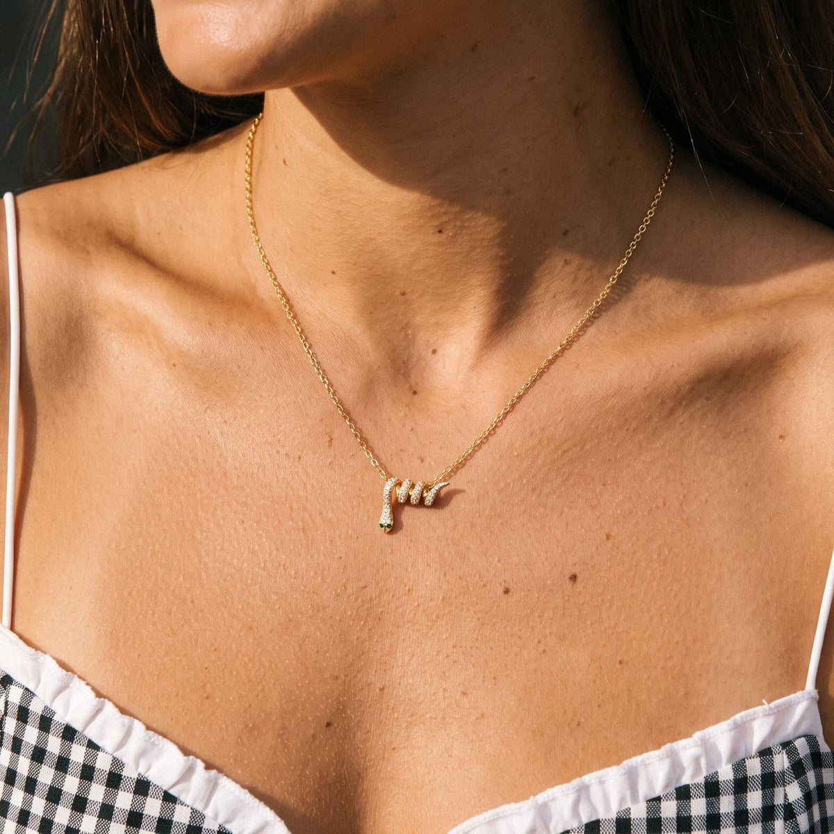 Woman wearing the Serena pavé snake gold necklace at the collarbone in a gingham top