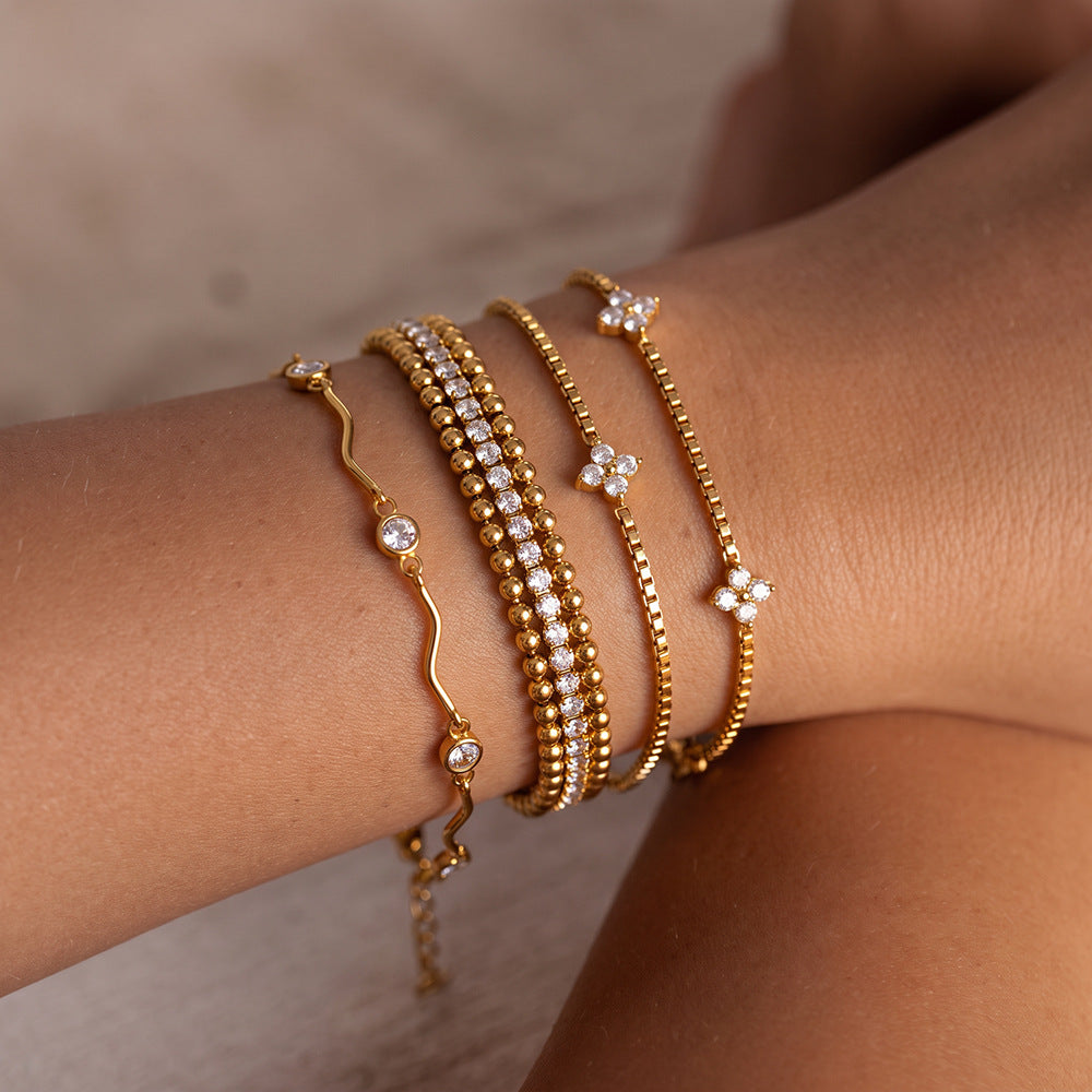 Sofia bead tennis bracelet worn in a wrist stack of four gold bracelets