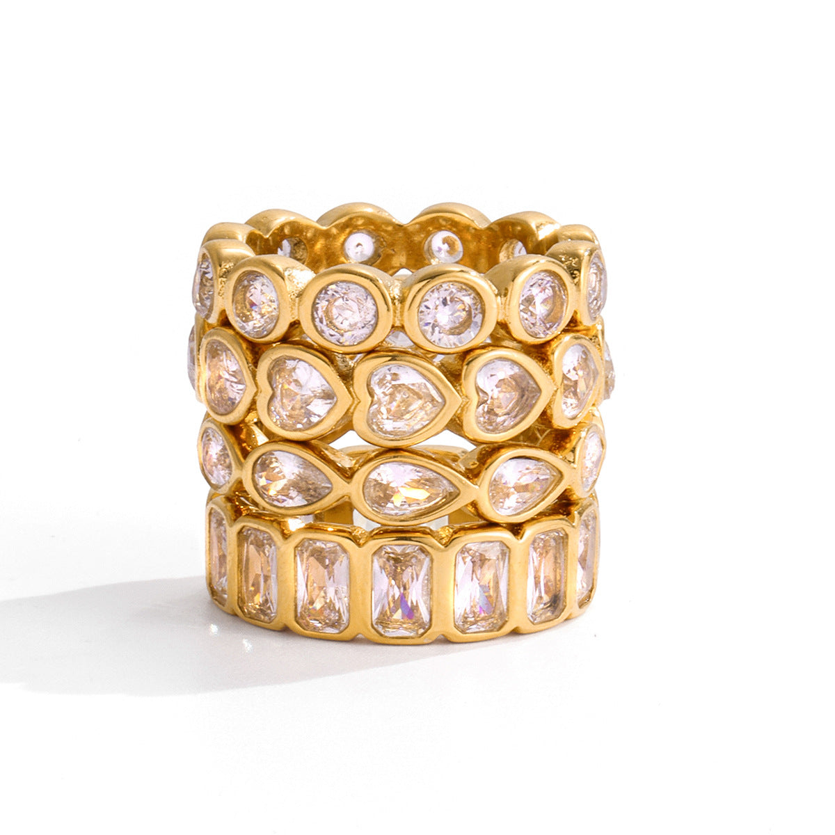 Stack of four clear crystal eternity gold rings, the baguette band at the bottom