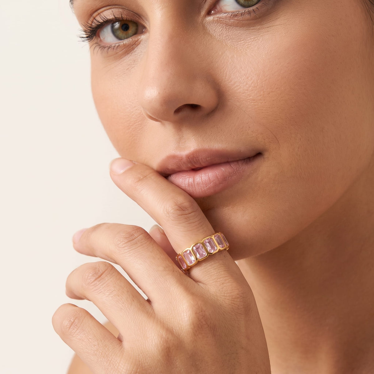 Woman wearing the Sophie pink baguette gold ring on the hand with index finger near her lips