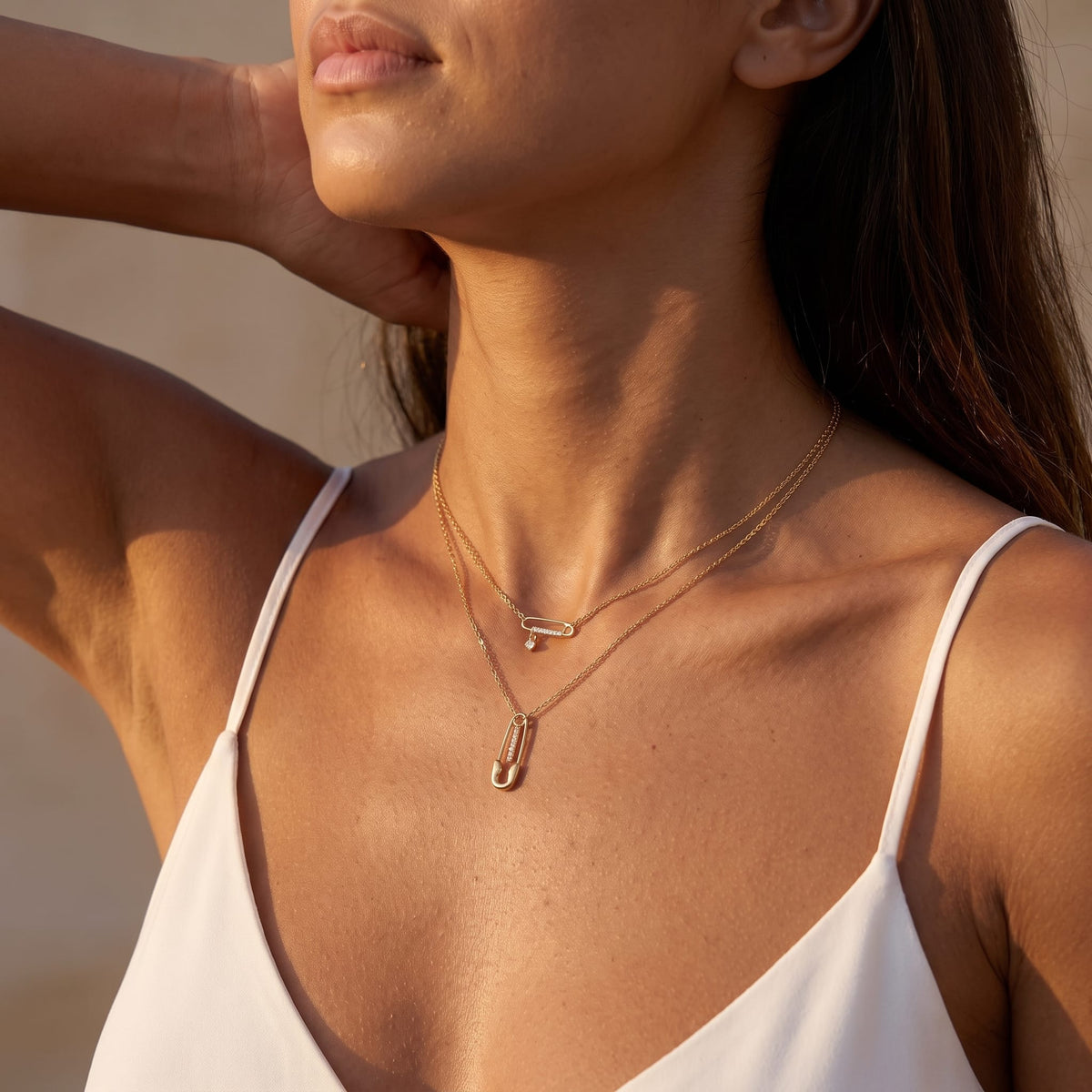 Woman wearing the Stella safety pin gold necklace at the throat in warm sunlight