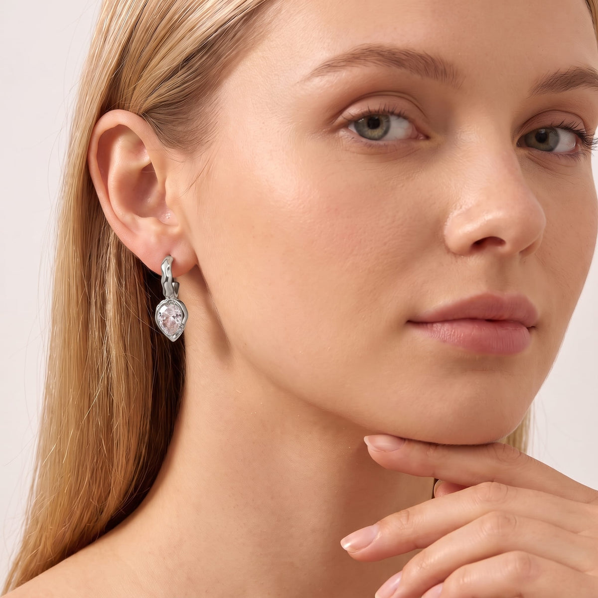 Woman wearing the Victoire hammered teardrop silver earrings on her ear with hand under chin