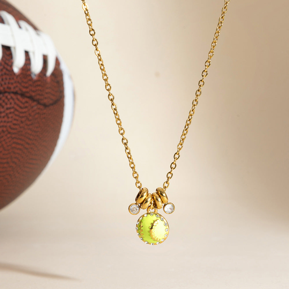 Vida softball charm necklace hanging beside a leather football on a cream backdrop
