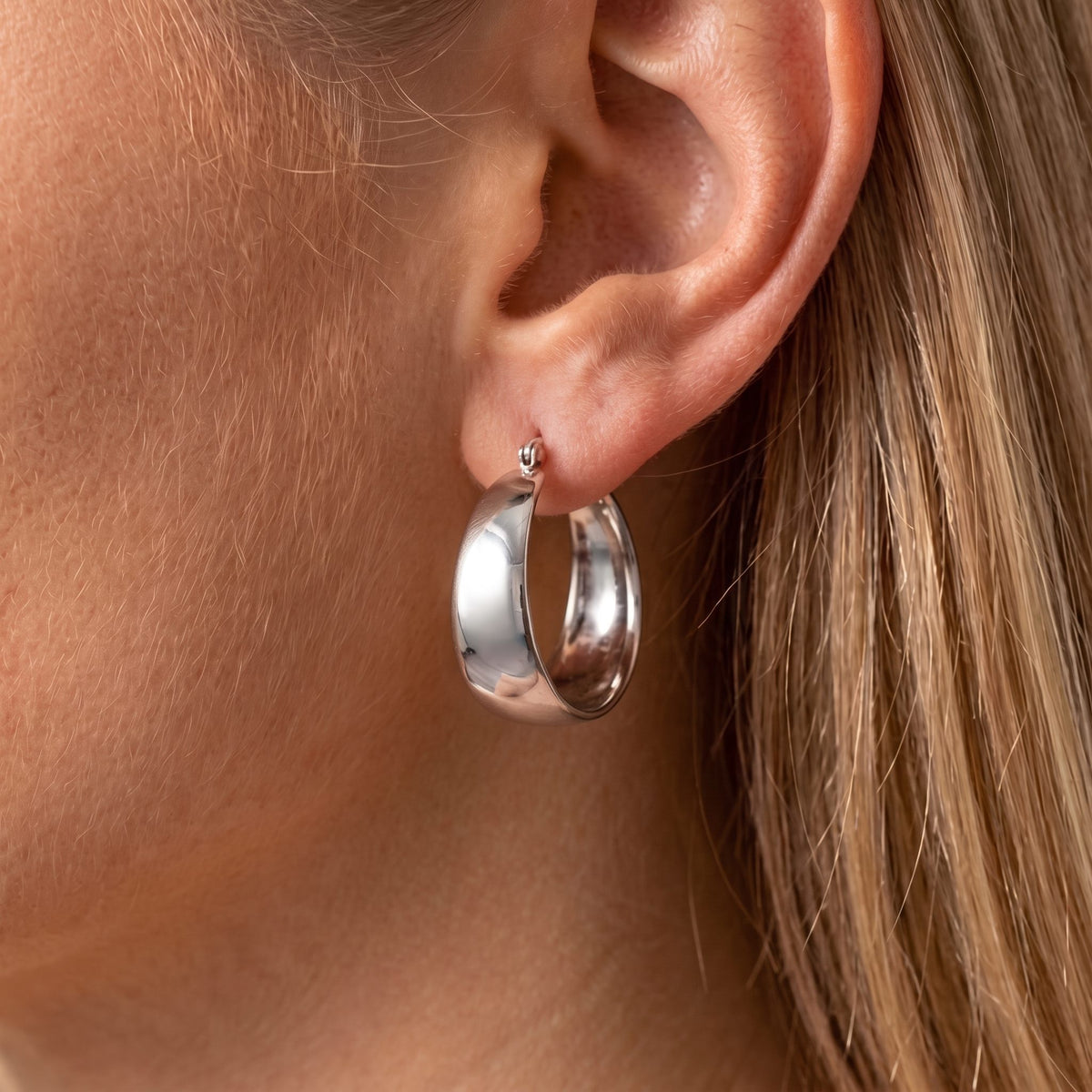 Close view of the Vivienne wide silver hoop with a smooth, high-shine finish