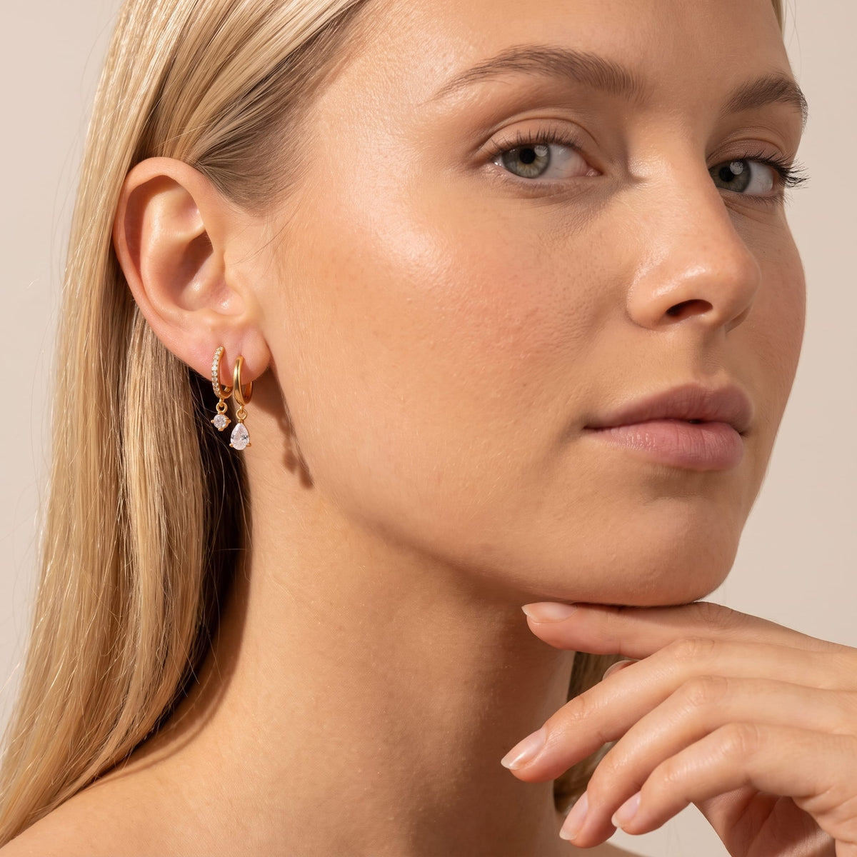 Woman wearing the Ysaline double hoop gold earrings on her earlobe resting her chin on hand