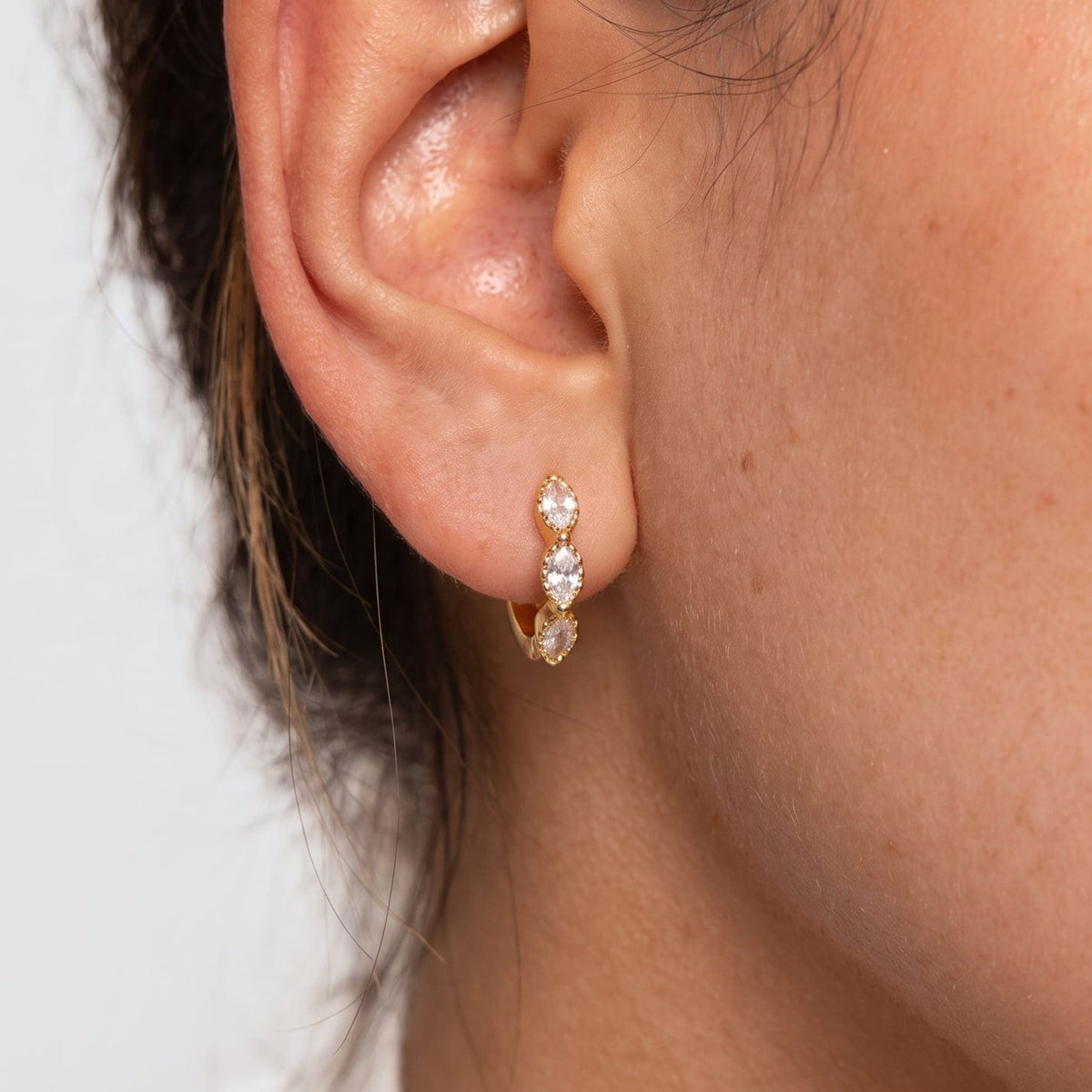 Woman wearing the Zoé marquise huggie gold earrings on the ear